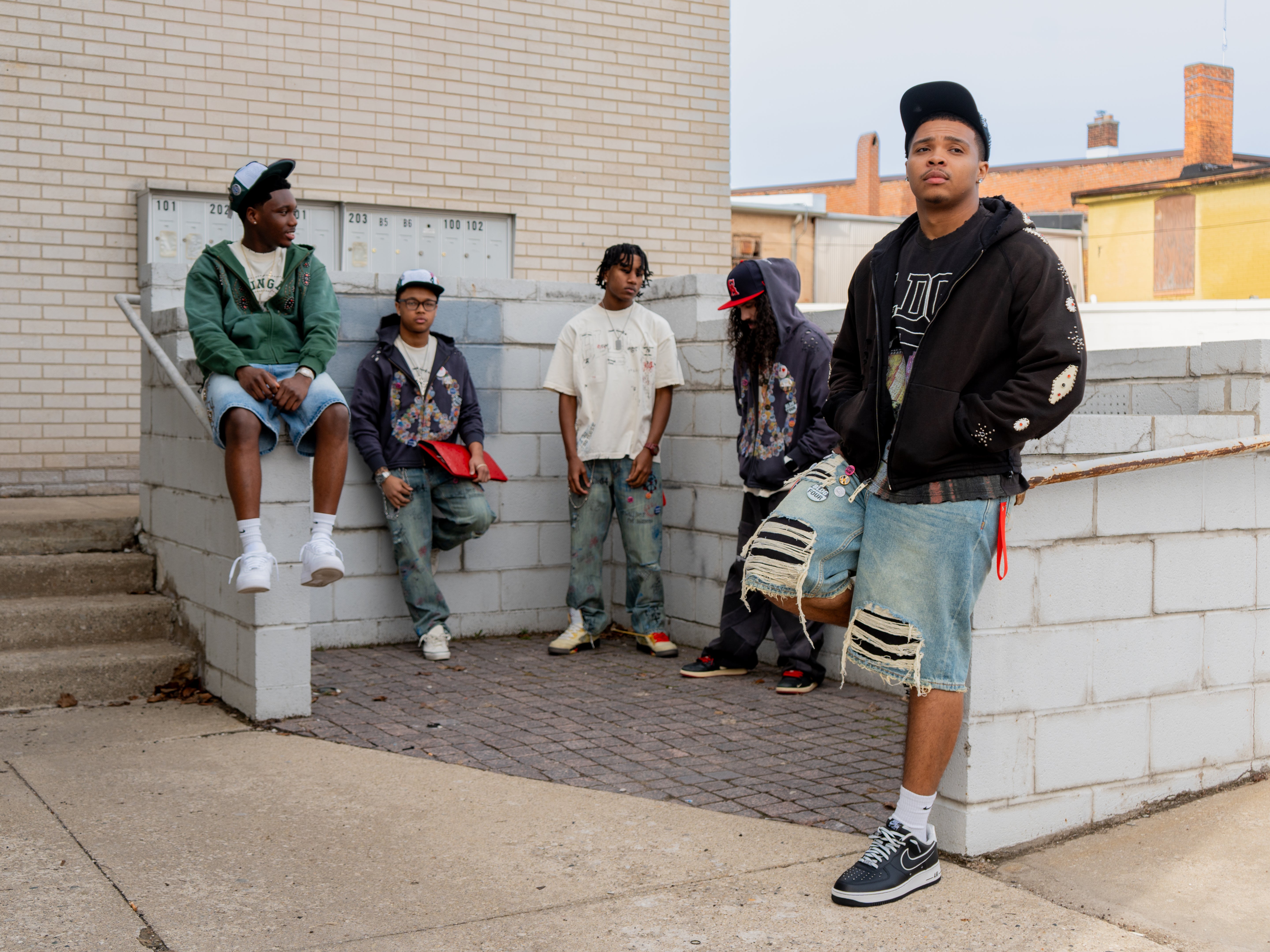Group of young men standing and sitting on a set of stairs in an urban setting. Wearing BLDG4 clothing from Puffer Reds